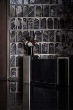 a vase filled with flowers sitting on top of a counter next to a wall covered in pictures