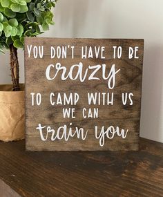 a wooden sign that says you don't have to be crazy to camp with us we can train you