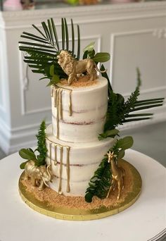 a three tiered wedding cake decorated with greenery and animals