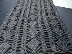 a crocheted table runner on a black surface