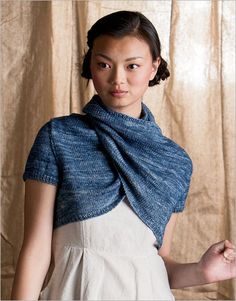 a woman wearing a blue shawl standing in front of a curtain