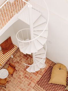 an overhead view of a spiral staircase in a home with two chairs and a rug on the floor