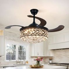 a ceiling fan in the middle of a kitchen with chandelier hanging from it