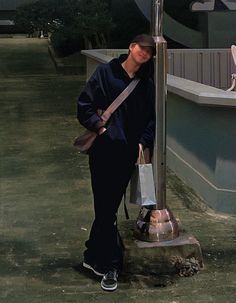 a person leaning against a pole with a shopping bag