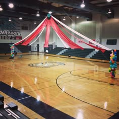 an indoor basketball court decorated with balloons and streamers