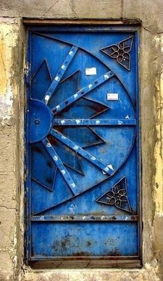 a blue door that is on the side of a building with an arrow in it