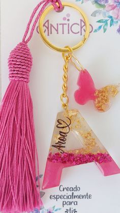 a pink tasseled keychain hanging from a gold plated metal hook