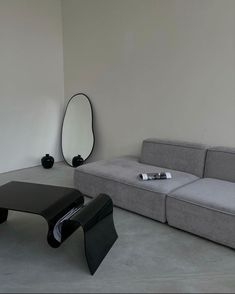 a living room with a couch, mirror and table on the floor in front of it