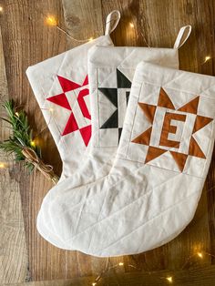 two christmas stockings on a wooden table with lights around them and one has a star design