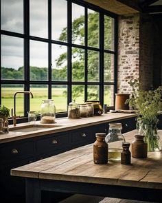 a kitchen counter with jars and vases on it next to a window that looks out onto a field