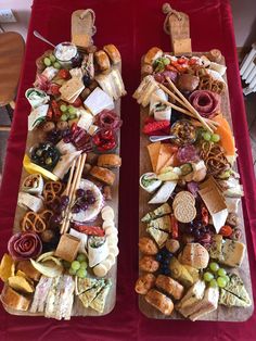 two trays filled with different types of food on top of a red table cloth