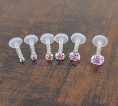 five pairs of jeweled nose studs on a wooden surface