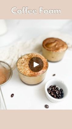 three cupcakes sitting on top of a white table next to some coffee beans