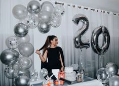 a woman standing in front of a table with balloons and presents