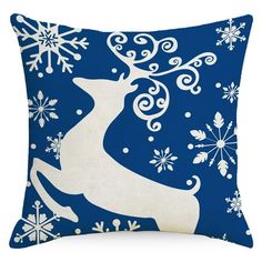 a blue pillow with white snowflakes and a deer silhouette on the front, against a dark blue background