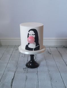 a white cake with black and pink frosting on it's side, featuring a woman blowing a bubble