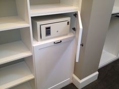 an open white cabinet with a keypad on the door and shelves in front of it