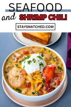 seafood and shrimp chili in a white bowl with sour cream on top, next to bread