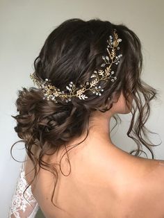 the back of a woman's head wearing a bridal hair comb with gold leaves on it