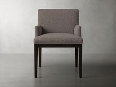 an upholstered chair sits in front of a plain wall with no one on it