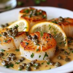 seared scallops with capers and olives in a white sauce on a plate