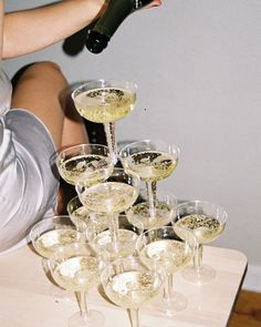 a woman is pouring champagne into wine glasses