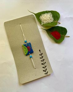 a pair of earrings sitting on top of a piece of paper next to some leaves