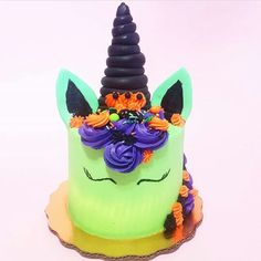 a green cake decorated with flowers and a unicorn's horn