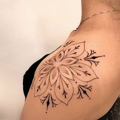 a woman's shoulder with a tattoo design on the back of her left shoulder