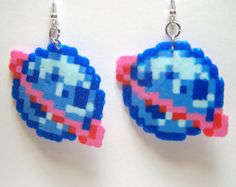 some type of earrings that are made to look like pixel art beads with pink, blue and white designs on them