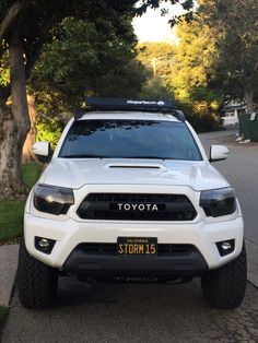 a white truck parked on the side of a road next to a tree filled street