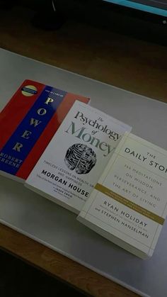 three books are sitting on top of a glass table in front of a computer monitor