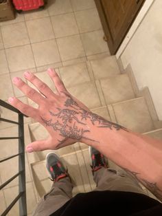 a man's hand with a tattoo on it sitting in front of a stair case