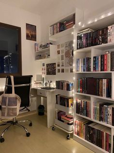 a room filled with lots of books next to a desk and computer chair in front of a window