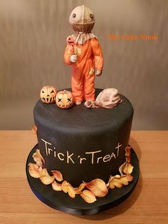 there is a halloween cake with a trick'n'treat on the top and pumpkins around it