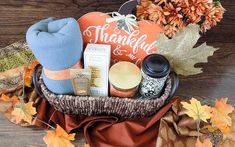 a basket filled with items sitting on top of a wooden table next to autumn leaves