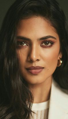 an image of a woman with long hair and brown eyeshade looking at the camera