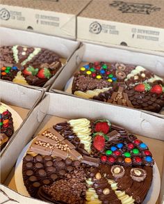 four boxes filled with cakes covered in chocolate frosting and toppings on top of each other