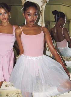 two women in pink and white dresses standing next to each other with their hands on their hips