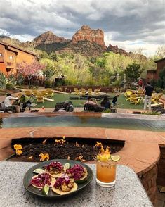 a plate of food sitting on top of a table next to a fire pit with mountains in the background