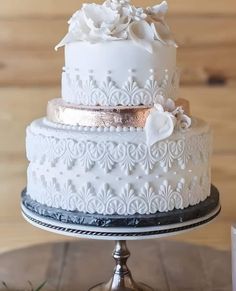 a three tiered wedding cake with white frosting and flowers on the top layer