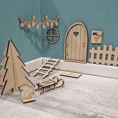 wooden cutouts are arranged on the floor in front of a blue wall with a tree and sleigh