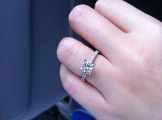 a woman's hand with a diamond ring on top of her finger in the car