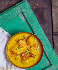 a bowl filled with food sitting on top of a green table next to a napkin