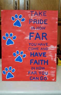 a red sign with blue paw prints on it that says take pride in how far you have come and have faith in how far you can go