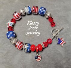 This lovely Patriotic Bracelet is made with beautiful and unique Artisan Lampwork Beads.  Perfect for the 4th of July, Memorial Day, or any Patriotic Occasion.  Another "One of a Kind" jewelry creation by Klassy Joolz. *  Artisan Patriotic Lampwork Barrel Shaped Beads - Art Beads *  Artisan Lampwork Rondelle Spacer Beads - Art Beads *  Swarovski Crystals *  Star Enamel Charm Dangle *  Star Enamel Focal Bead *  Heart/Flag Dangle Charm *  Silver Beads, Bead Caps and Crystal/Rhinestone Rondell Spac Patriotic Colorful Beads Bracelet For Gift, Patriotic Beaded Bracelets With Colorful Beads As Gift, Patriotic Round Beads Jewelry Gift, Patriotic Jewelry With Colorful Beads As Gift, Handmade Patriotic Bracelets For Gift, Patriotic Beaded Bracelets For Gifts, Handmade Patriotic Multicolor Beaded Bracelets, Patriotic Colorful Beaded Jewelry Gift, Handmade Adjustable Patriotic Bracelets