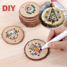 a person is using a pen to draw on wood slices with christmas decorations in the background