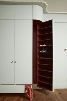 an open closet with shoes in it on the floor next to a white wall and wooden floors