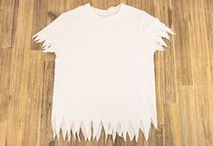 a white t - shirt that has been cut in half and is sitting on the floor