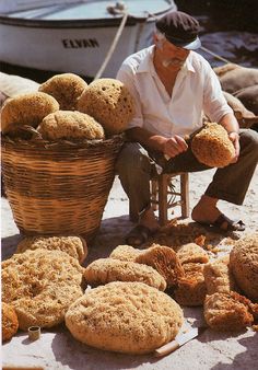 a man sitting on the ground next to baskets filled with bread and other items in front of him